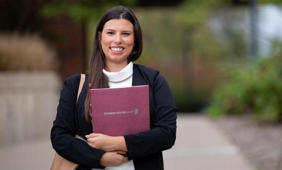 An MBA graduate student from Hamline's 商学院 holding a folder and smiling at the camera