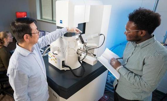 Two people using an electron microscope in Hamline's College of Liberal Arts