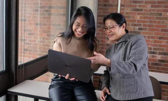 A Hamline student and her advisor looking at a laptop together and smiling