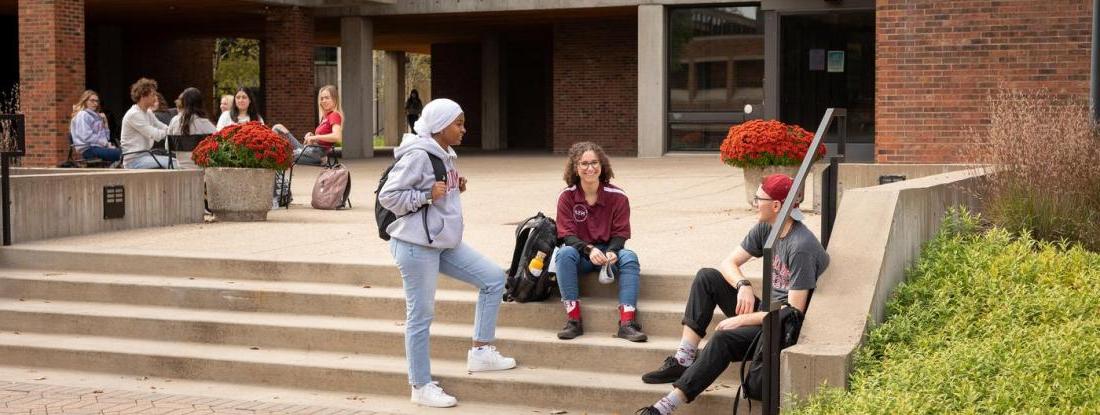 Three Hamline students gathered on a set of outdoor stairs on campus
